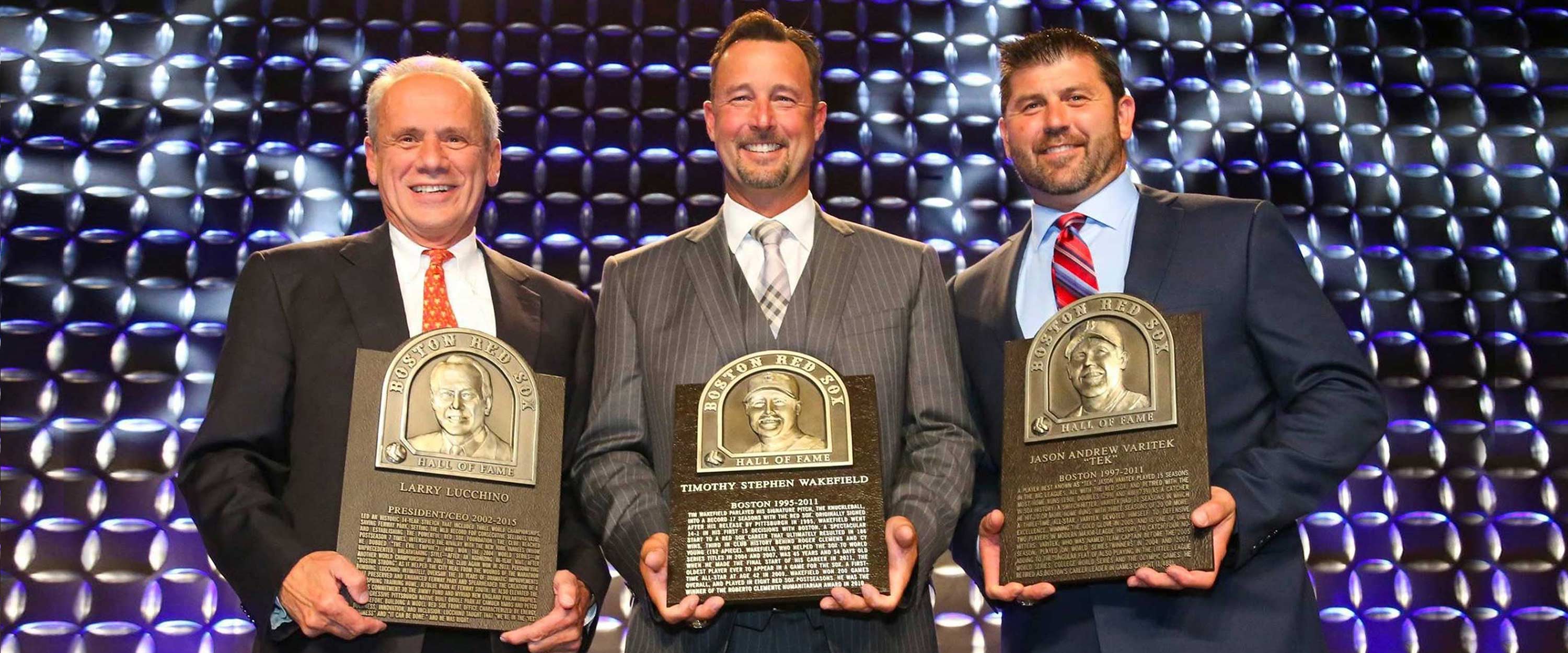 Photo from the event of Larry Lucchino, Tim Wakefield, and Jason Varitek holding their Hall of Fame plaques and smiling