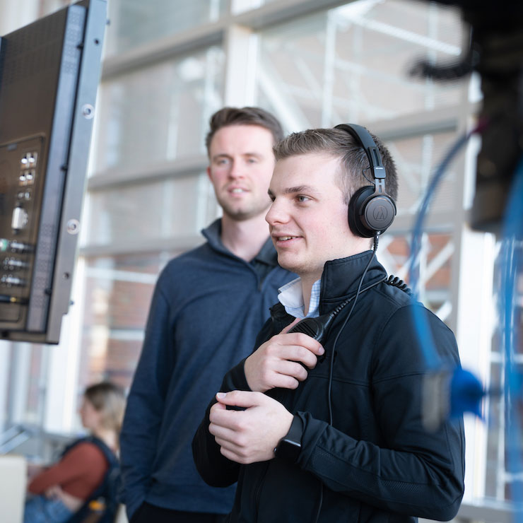 Evan working on set of a video shoot, wearing headphones