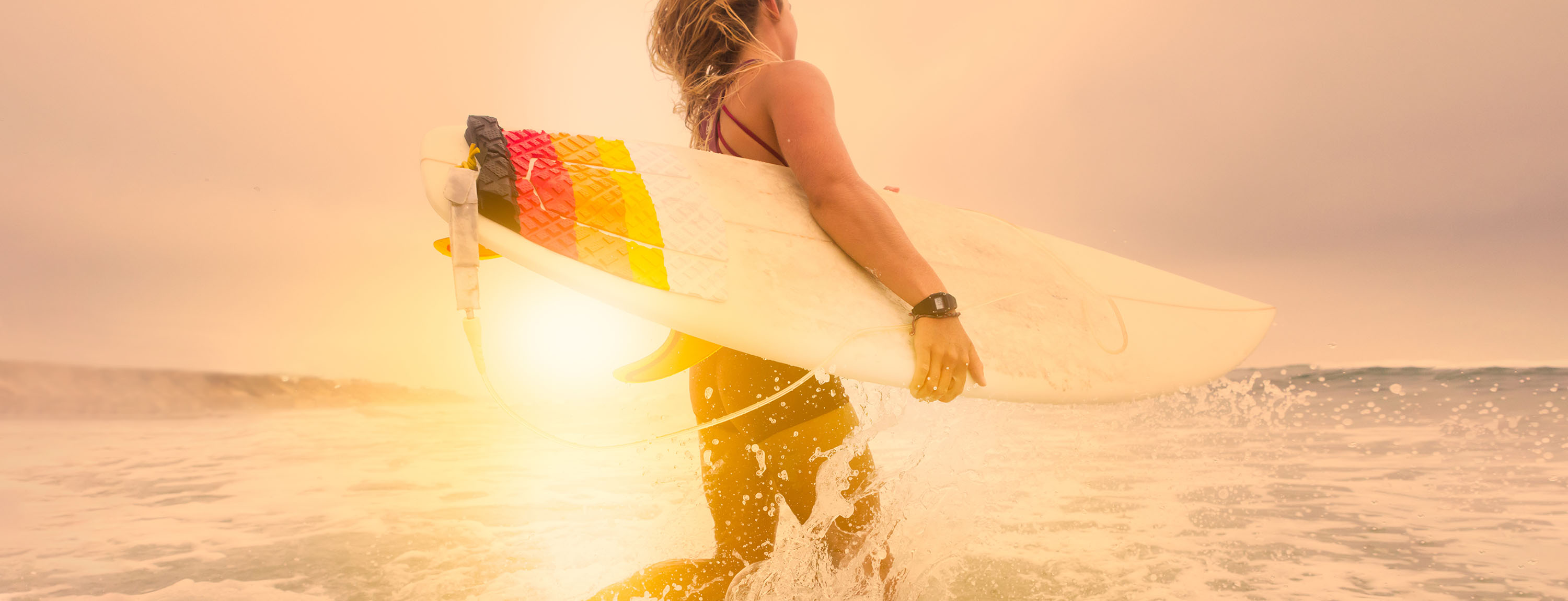 woman on beach heading out into the waves to surf in California