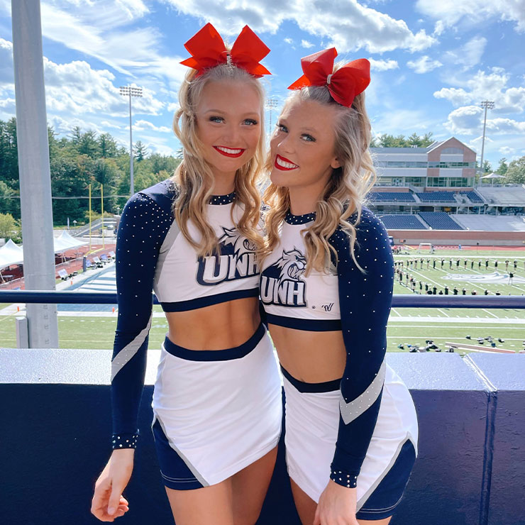 Sydney and a teammate cheerleading at a UNH football game