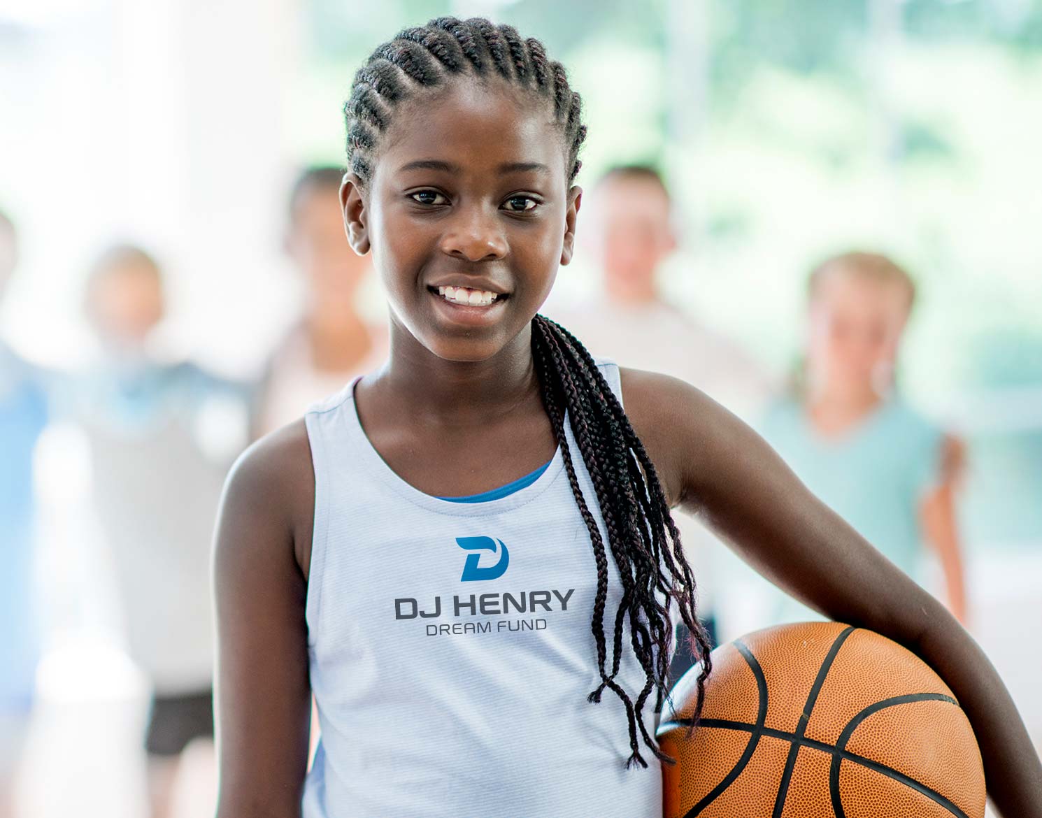 Young child playing basketball wearing shirt with DJ Henry Dream Fund logo