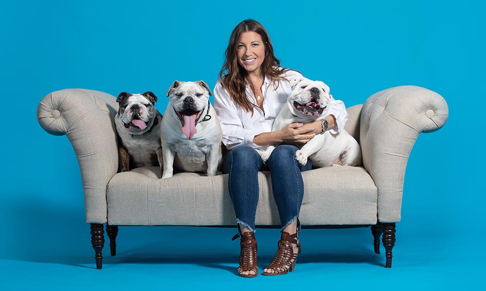 MSPCA-Angell portrait project fundraiser donor on couch with 3 dogs and blue backdrop