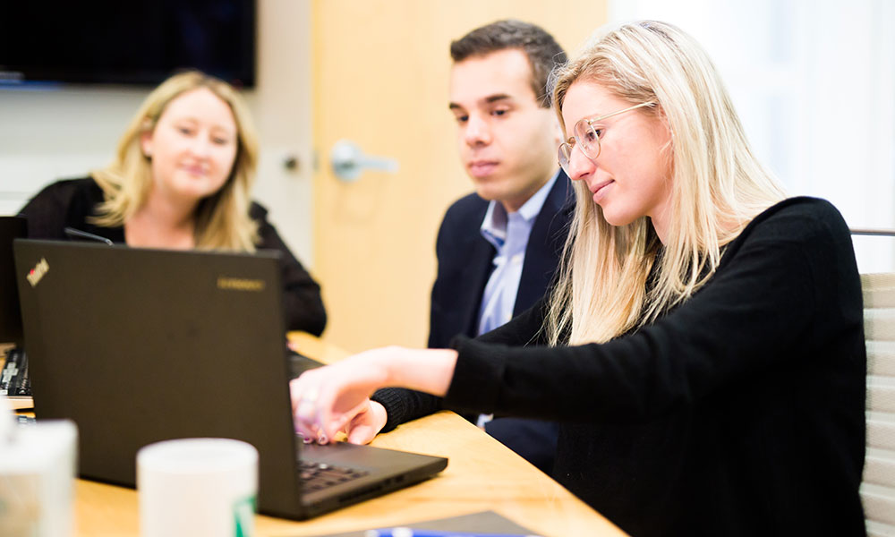 V2 Communications colleagues looking at laptop discussing