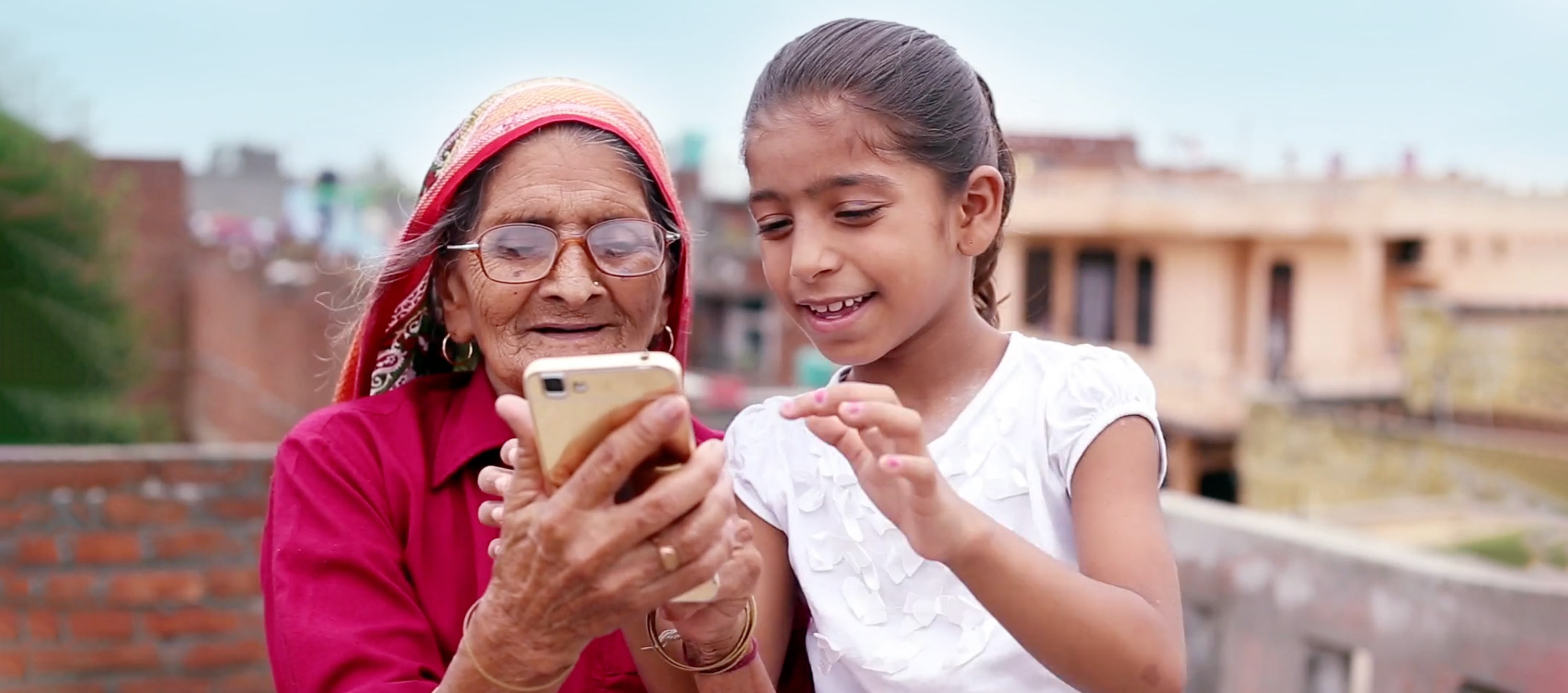 Elderly village women using mobile phone with her granddaughter in India