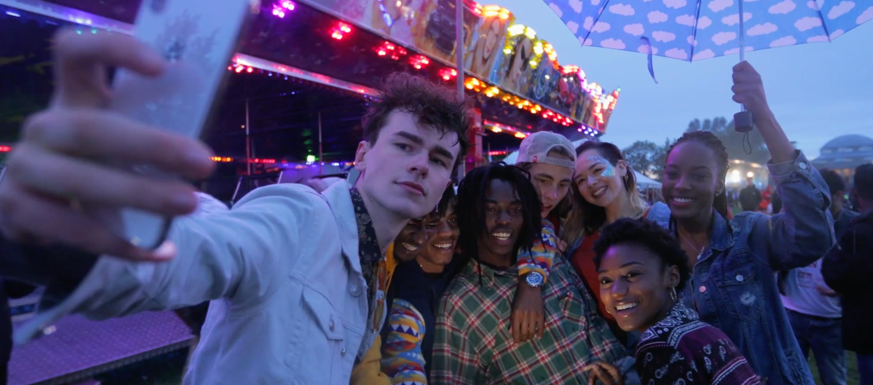 Diverse group of young adults taking a group selfie at a carnival